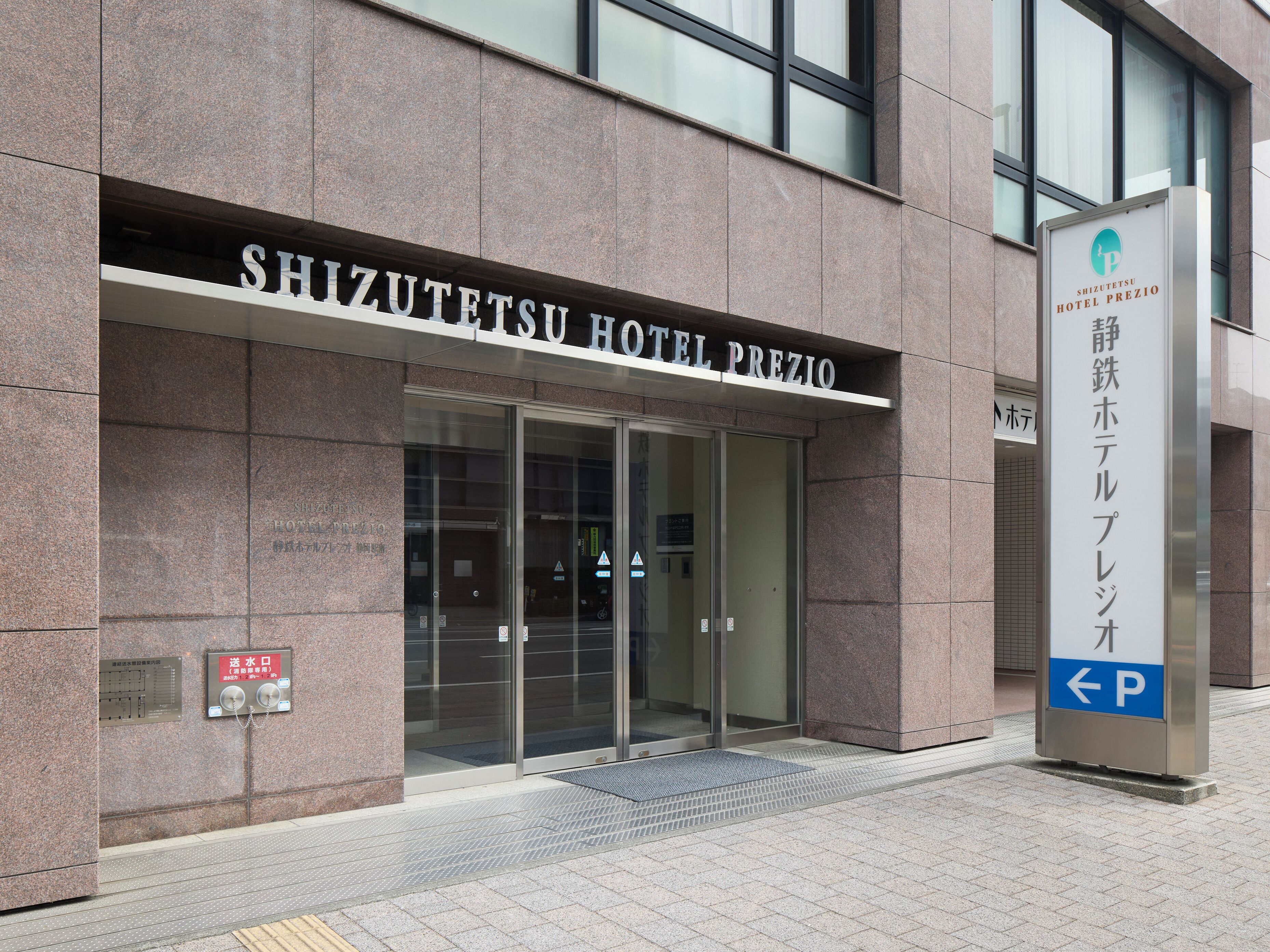 The exterior of the Shizuotetsu Hotel Prezio with a clear entrance, signage, and a parking direction sign.