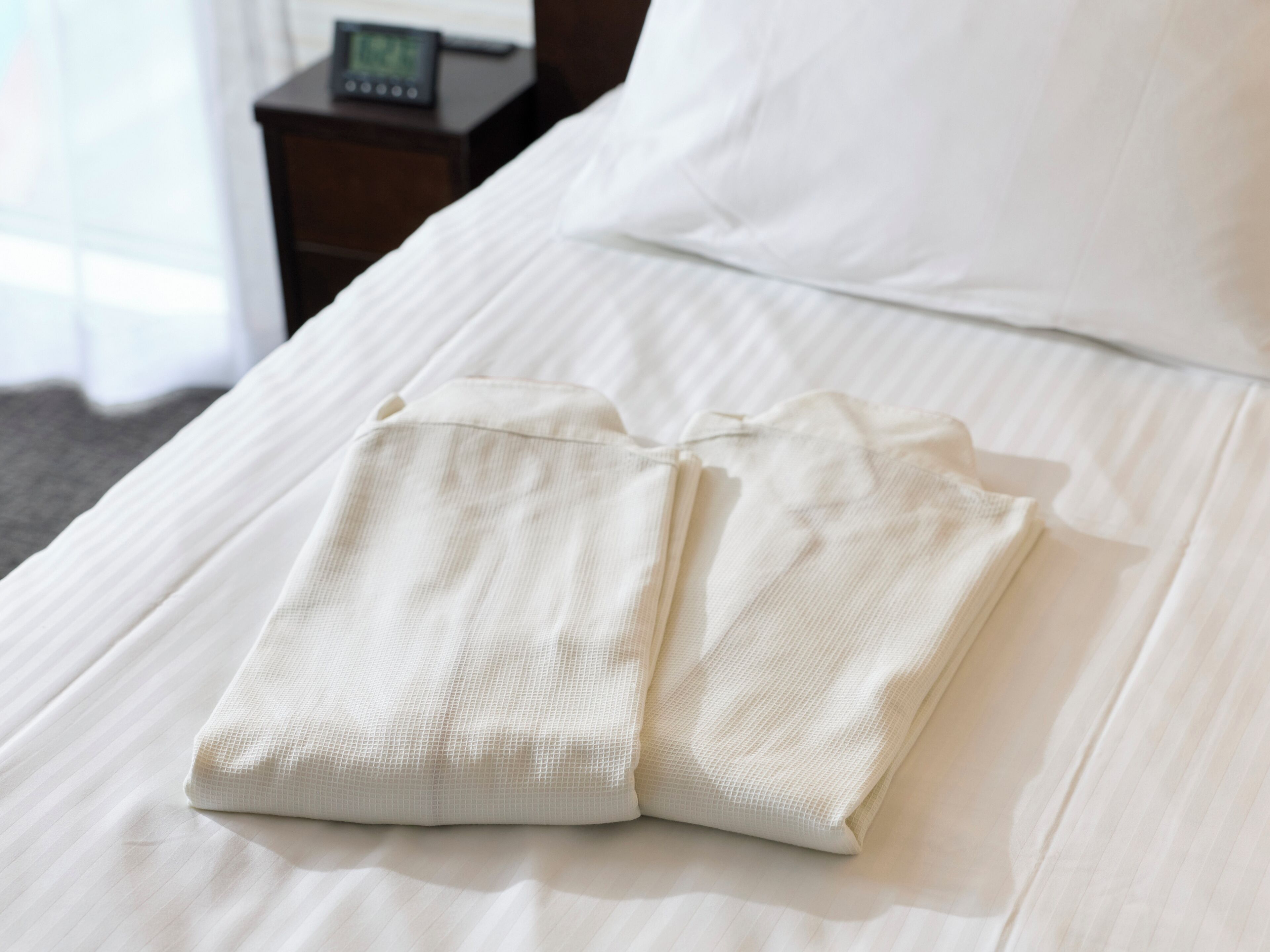 Una cama bien hecha con una almohada y una prenda doblada encima.