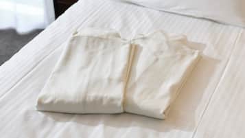Una cama bien hecha con una almohada y una prenda doblada encima.