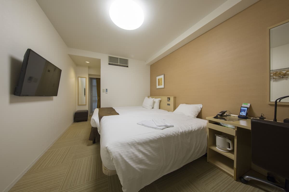 Une chambre d’hôtel équipée d’un lit, d’un bureau avec un téléphone et une machine à café, d’une télévision et d’un miroir.