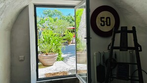 A doorway leading to an outdoor garden with potted plants and a speed limit sign.