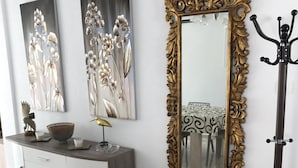 A modern interior with a white cabinet, two floral wall art pieces, a large ornate mirror, and a floor lamp. - Luxury Villa south facing-Beach 500m-Private heated pool-English TV-WiFi-BBQ (SANTIAGO DE LA RIBERA)