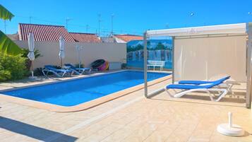 Een buitenzwembad, een verwarmd zwembad, ligstoelen bij het zwembad