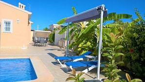 A poolside area with lounge chairs, a covered seating area, and a building with a tiled roof. - Luxury Villa south facing-Beach 500m-Private heated pool-English TV-WiFi-BBQ (SANTIAGO DE LA RIBERA)