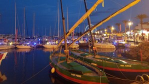 Un port de plaisance au crépuscule, où de nombreux bateaux sont amarrés, dont un bateau vert nommé « BEL ANGE » et un autre nommé « SAINT PIERRE ».