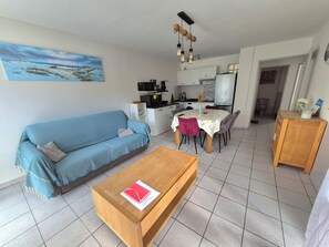 Un salon comprenant un canapé, une table basse et un coin repas avec une table et des chaises.