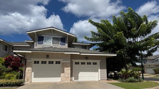 A two-story house with a garage, a driveway, and a large tree in the front yard. - Hawaii Condo Close to Beach, Golf, Pool and Restaurants (Kapolei)