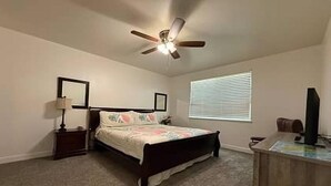 A bedroom with a bed, a desk, a ceiling fan, and a window with blinds. - Hawaii Condo Close to Beach, Golf, Pool and Restaurants (Kapolei)