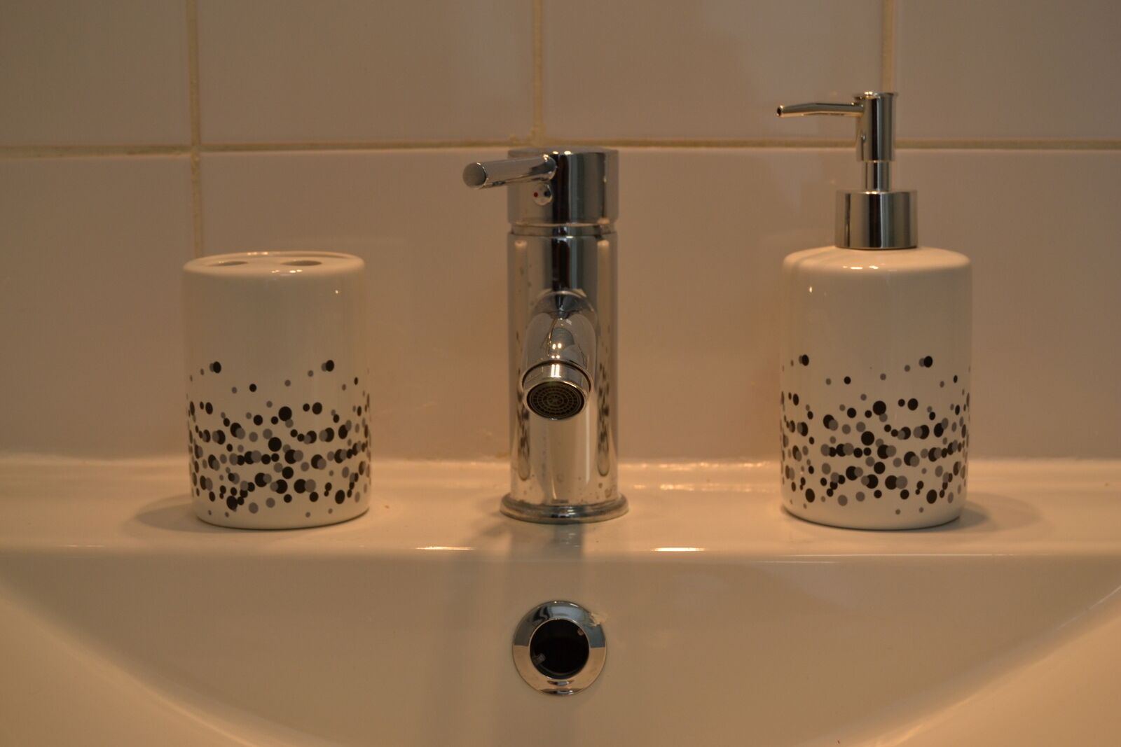 A bathroom sink with a chrome faucet, two soap dispensers, and a mirror.