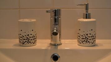A bathroom sink with a chrome faucet, two soap dispensers, and a mirror.