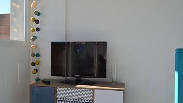 Uma TV Samsung sobre um móvel de madeira, com um armário decorado abaixo.