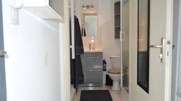 A compact bathroom with a toilet, sink, and mirror.