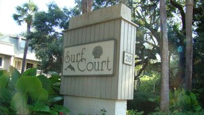 A sign for 'Surf Court' with a number '26' on it, surrounded by greenery and palm trees. - Surf Court 48- 1 Block To The Beach! (Hilton Head Island)