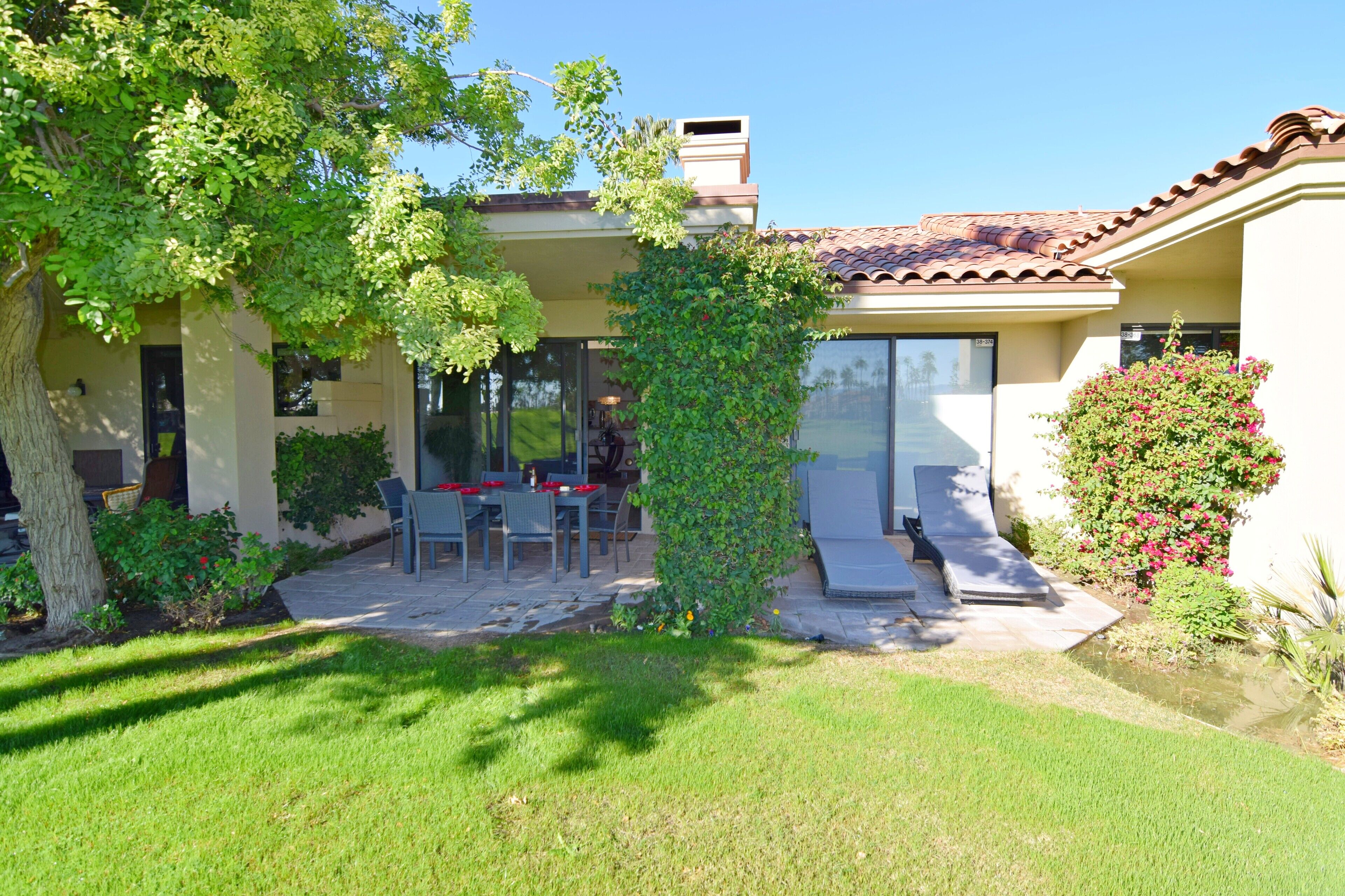 A house with a patio, a tree, and a small garden.