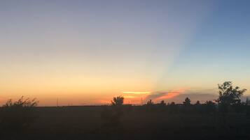A sunset over a flat landscape with sparse vegetation and a clear sky.