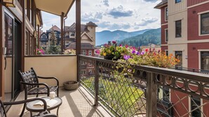 Un balcon avec vue sur les montagnes, une chaise et une table avec un livre.