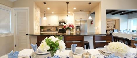 A modern kitchen with white cabinets, a central island, and pendant lighting.