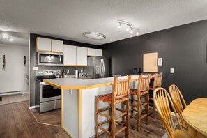 Une cuisine moderne dotée d’un îlot central, d’appareils électroménagers en acier inoxydable et de tabourets de bar en bois.
