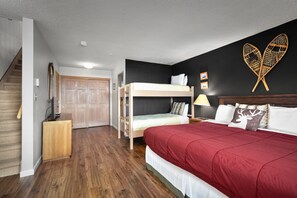 Ein Schlafzimmer mit Etagenbett, einem Doppelbett, Holzboden, einer Treppe, einem Kleiderschrank und einer Wanddekoration.