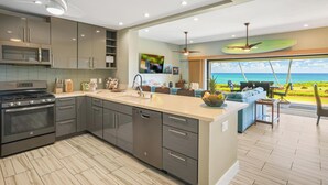 A modern kitchen with a large island, built-in appliances, and a view of the ocean. - Paradise Found | 2BR Condo | Ocean  Front Views | With AC (Kapaa)
