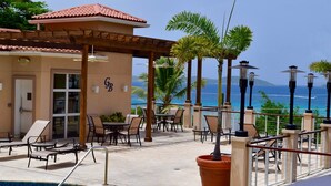 A poolside area with lounge chairs and a pergola overlooking the ocean.