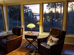 Relax in a serene space with a seating area featuring two armchairs and a side table, offering a view of the surrounding forest.