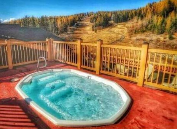 Relax in a hot tub on a raised deck overlooking a forested landscape.