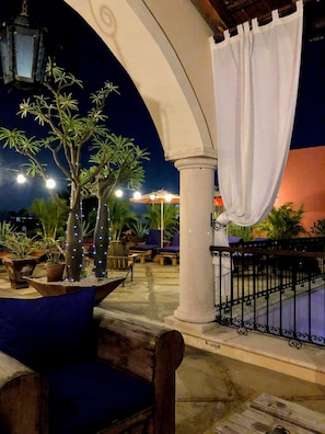 An outdoor seating area with a white column, blue chairs, and potted plants.