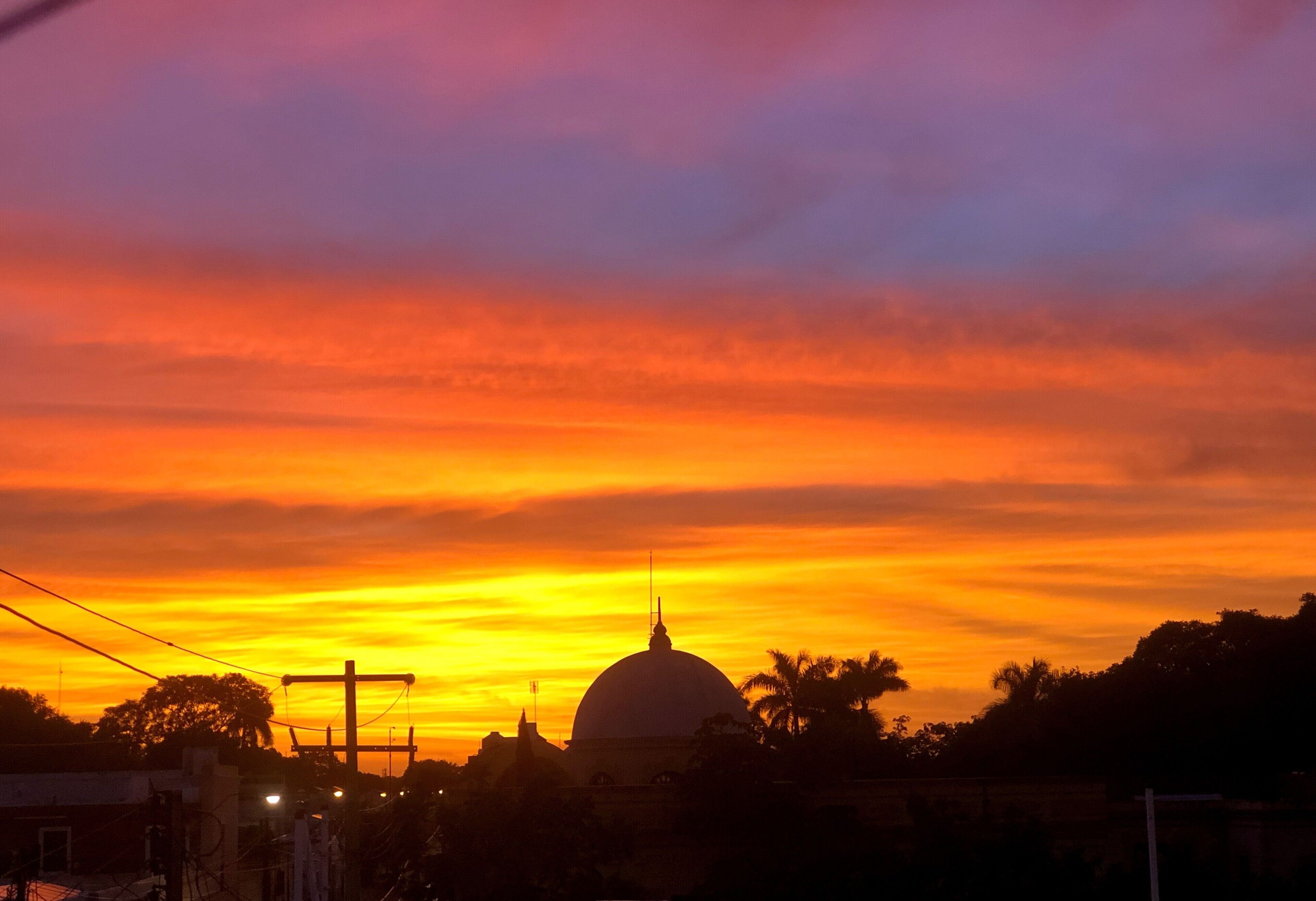Un tramonto con una struttura a cupola ben definita stagliata contro un cielo vivido.