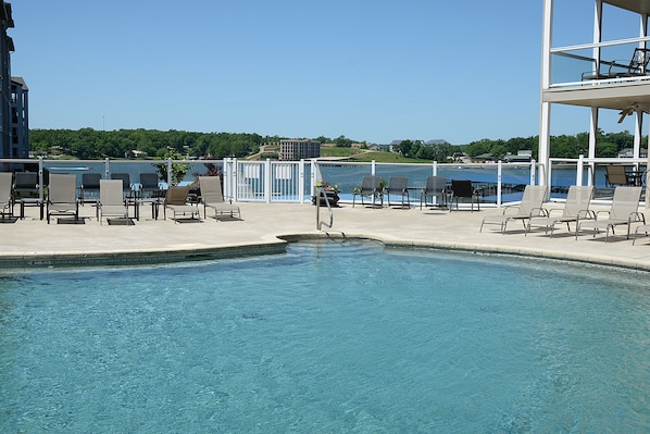 Relax by the serene pool surrounded by lounge chairs and a tranquil natural setting.