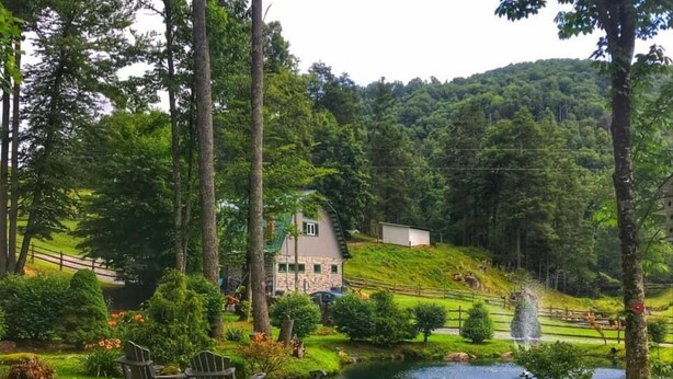 Un paysage paisible avec une maison en pierre, un étang et une chaise en bois.
