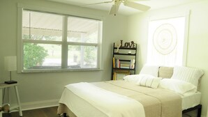 Un dormitorio con cama, ventilador de techo, estantería y ventana con persianas.
