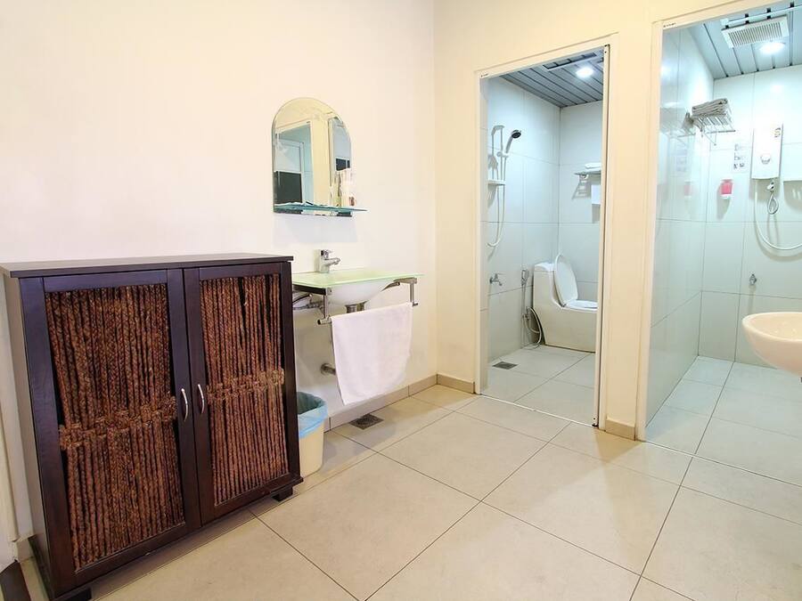 A bathroom with a cabinet, sink, mirror, and shower area.