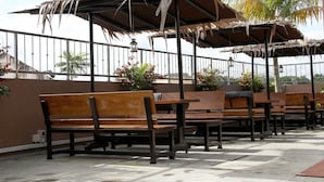 Terrassensitzgelegenheiten mit reetgedeckten Sonnenschirmen und Holzbänken.