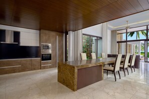 A modern kitchen with a granite island, built-in appliances, and a dining area with a large table and chairs.