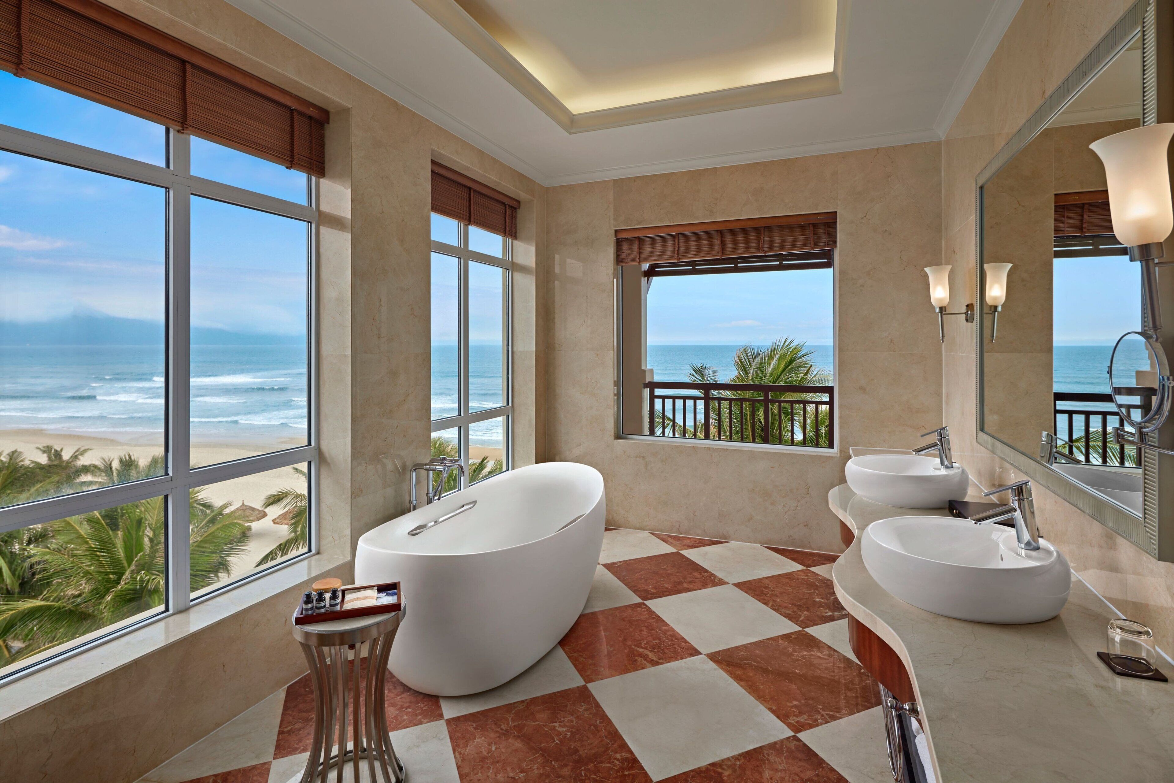 Un baño moderno con una bañera grande, dos lavamanos y vistas al océano.