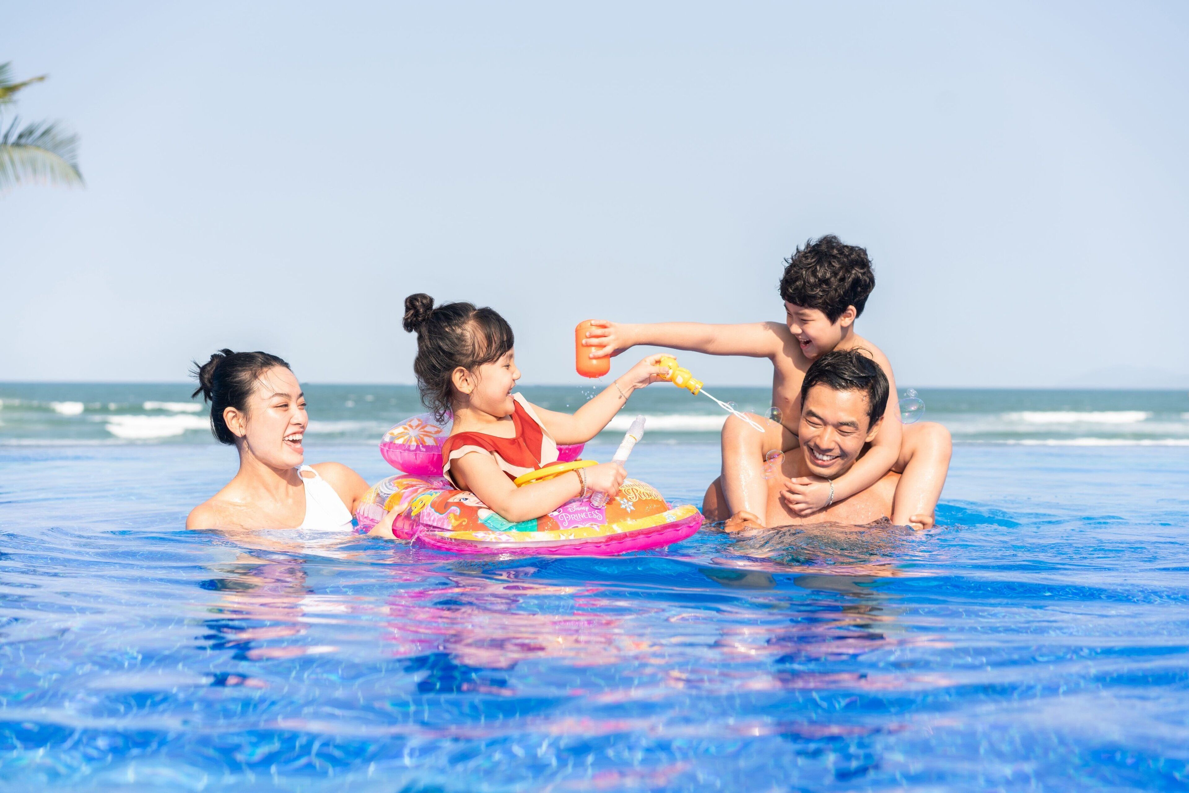 Una familia en una piscina con vista al océano.