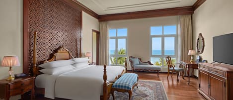 A spacious bedroom with a large bed, a sitting area with a view, and a television.
