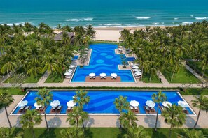 A resort with a central swimming pool, palm trees, and a beach view. - Danang Marriott Resort & Spa (Da Nang)