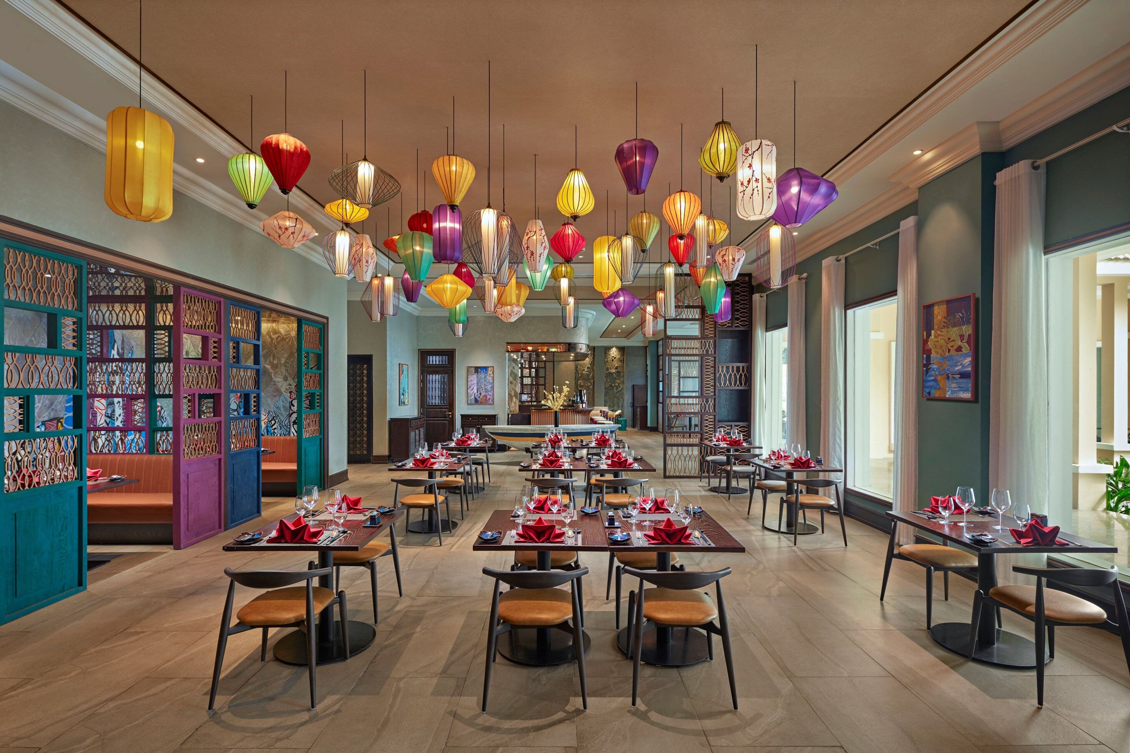 A spacious dining area with multiple tables set for dining, colorful hanging lanterns, and a view of the restaurant's interior.