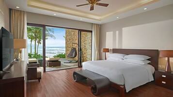 Habitación de hotel moderna con una cama grande, televisión, escritorio y vista al océano.