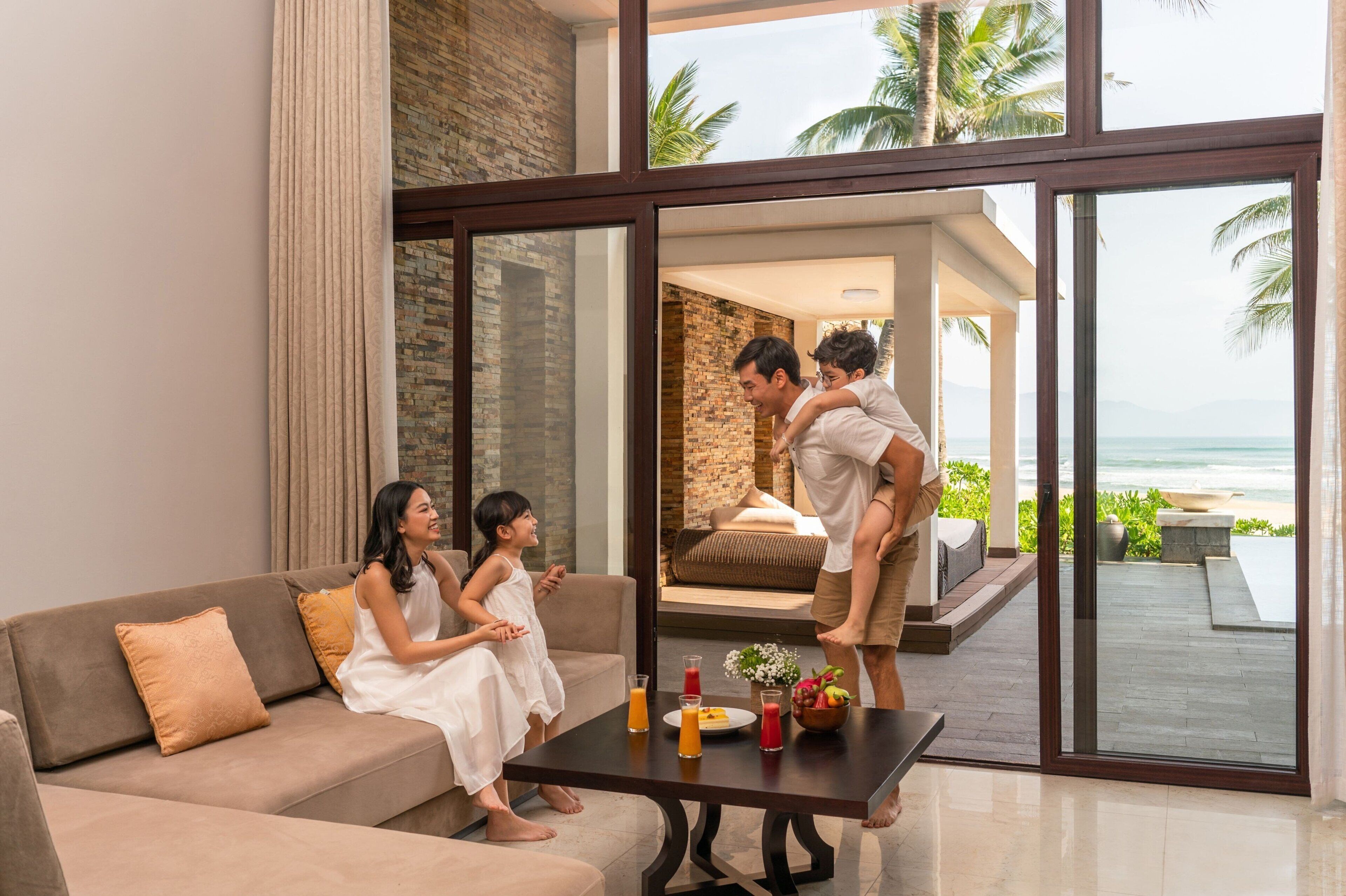 A modern living room with a large glass door leading to a balcony with a view of the sea.