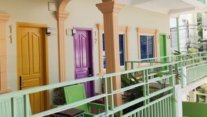 A multi-story building with balconies, each with a different colored door. - The Funky Village (Siem Reap)