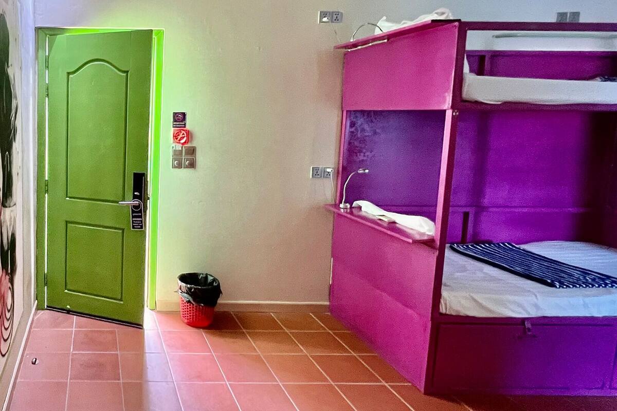 A hallway with a green door, a sink, and a bunk bed.