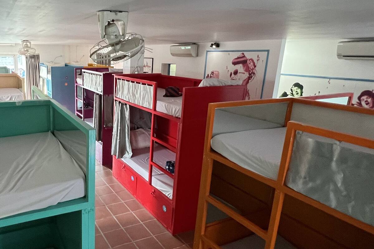A dormitory room with bunk beds, a fan, a window, and an air conditioning unit.