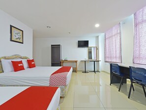 A hotel room with two beds, a desk, a chair, a TV, and a door.