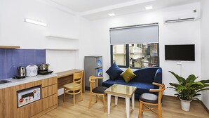 Un espace de vie compact comprenant un coin cuisine, un canapé, une petite table et un téléviseur.