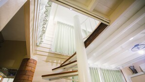 A staircase with a brick column and white railings, leading to a room with a window and a bicycle hanging on the wall. - Suan Tung Coffee (Chiang Rai)