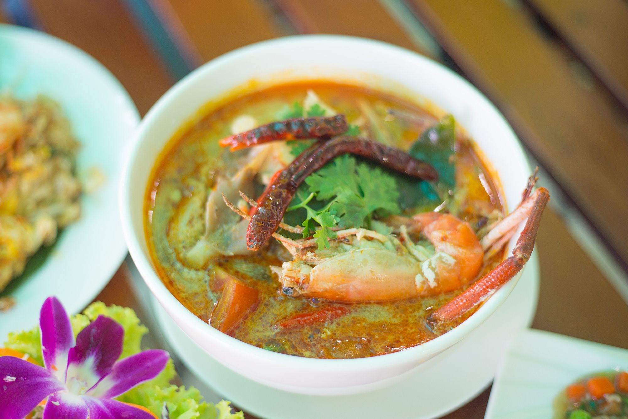 A bowl of soup with shrimp and herbs.