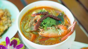 A bowl of soup with shrimp and herbs.